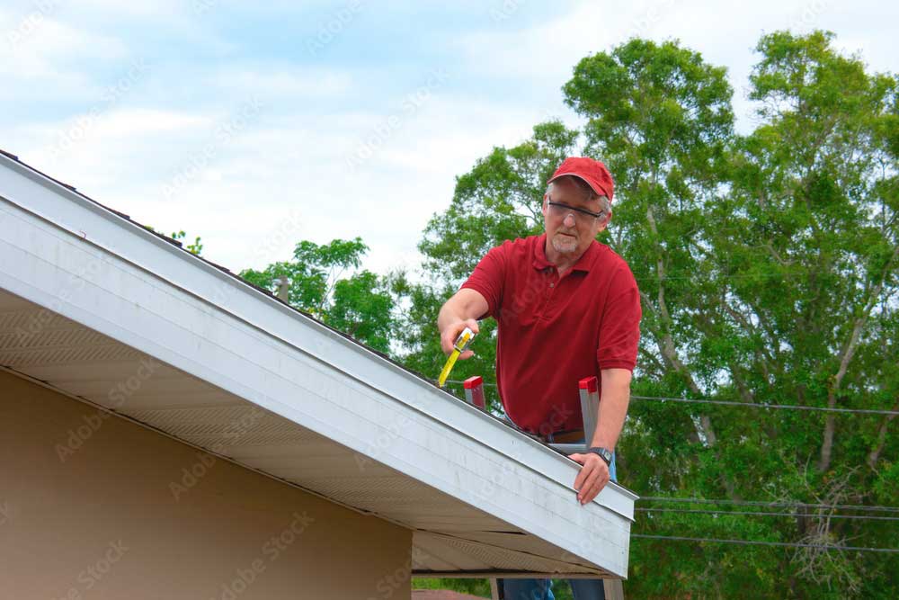 A roofing inspector using a tape measure as he inspects a newly installed roof