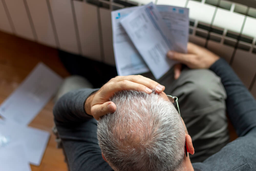 Man with his hand on his head while looking at his energy bill