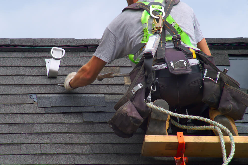 Roofer repairing shingles on a roof