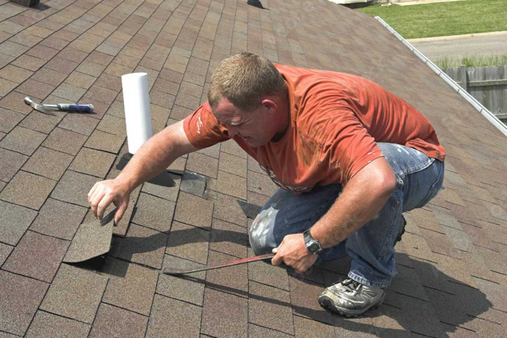 A roofer lifting a shingle during an inspection