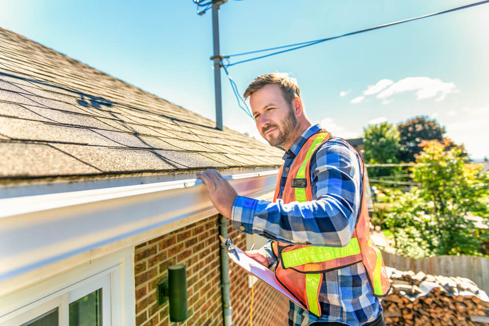 A roofing contractor performing a roof inspection on a home